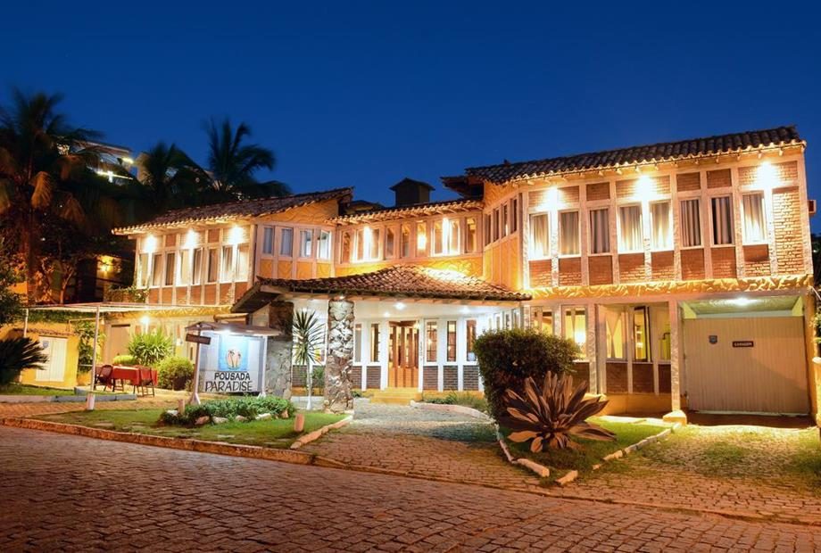 Fachada iluminada da Pousada New Paradise ao entardecer